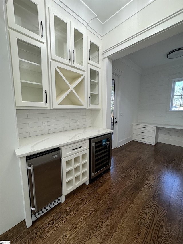 bar featuring dishwasher, wine cooler, light stone counters, ornamental molding, and dark hardwood / wood-style flooring