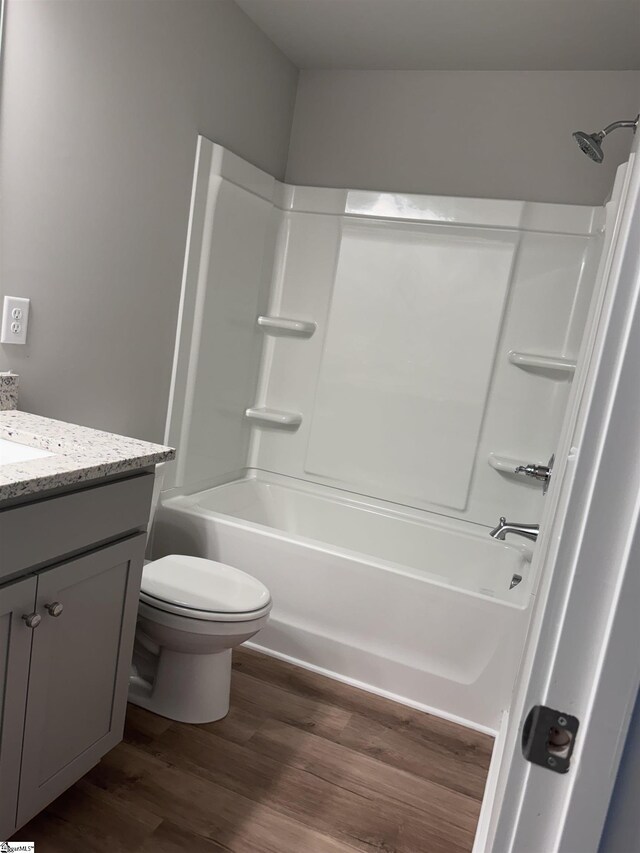 full bathroom featuring hardwood / wood-style flooring, vanity, shower / bathtub combination, and toilet