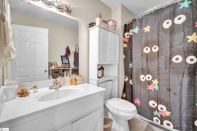 bathroom with vanity, toilet, a textured ceiling, and tile patterned flooring