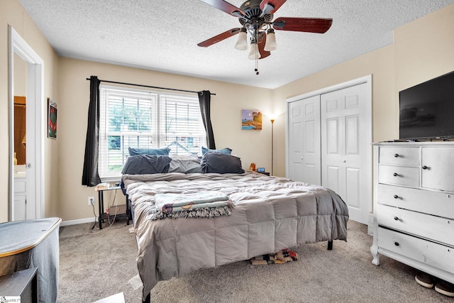 bedroom with a textured ceiling, light colored carpet, a closet, and ceiling fan