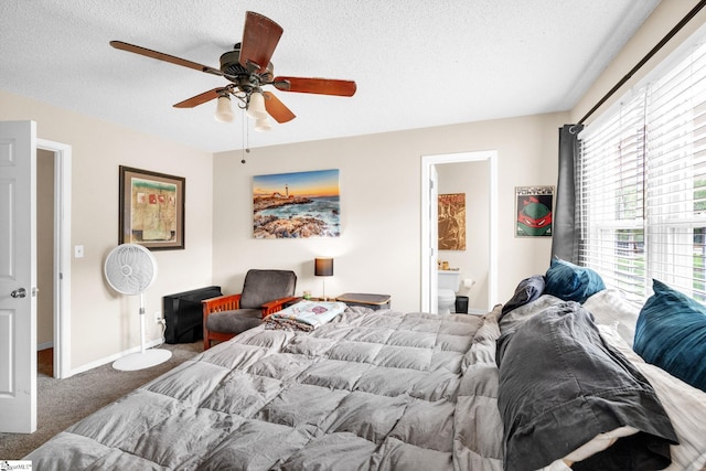 carpeted bedroom featuring a textured ceiling, ensuite bathroom, and ceiling fan