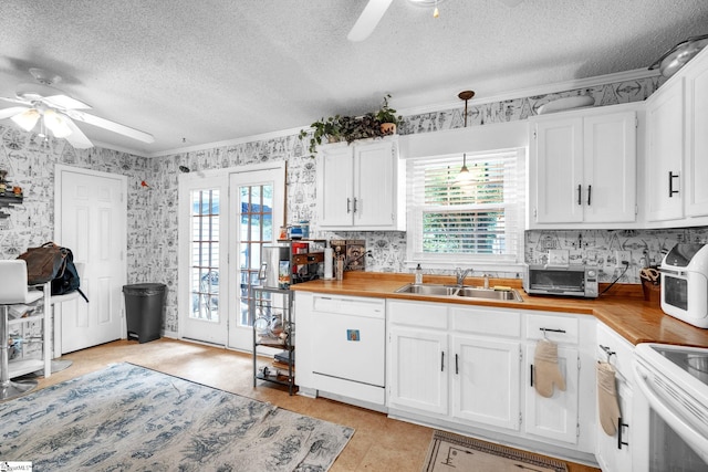 kitchen featuring ceiling fan, white cabinets, sink, white dishwasher, and butcher block countertops