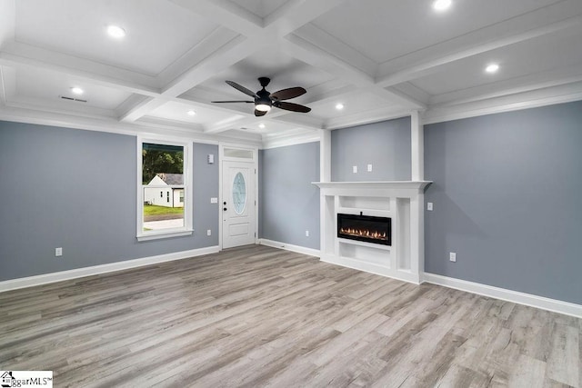 unfurnished living room with a warm lit fireplace, baseboards, coffered ceiling, beamed ceiling, and wood finished floors