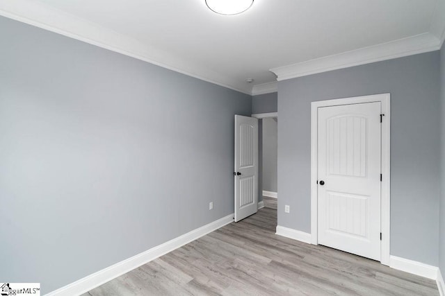 unfurnished bedroom with light wood-style flooring, baseboards, and crown molding