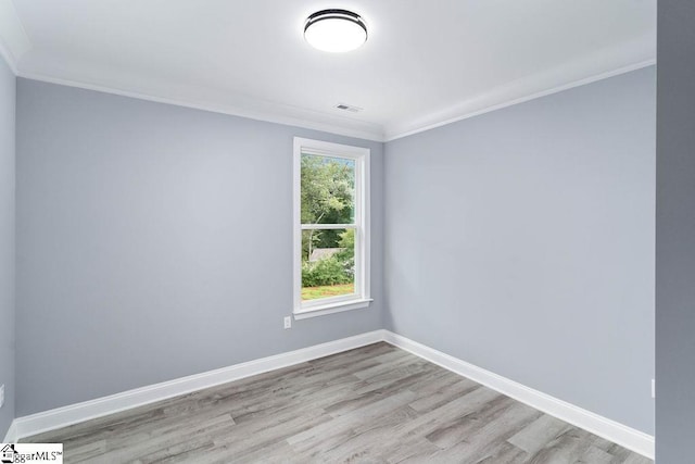 unfurnished room featuring crown molding, wood finished floors, visible vents, and baseboards