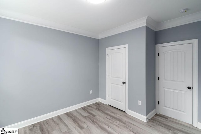 unfurnished bedroom featuring ornamental molding, light wood-type flooring, and baseboards