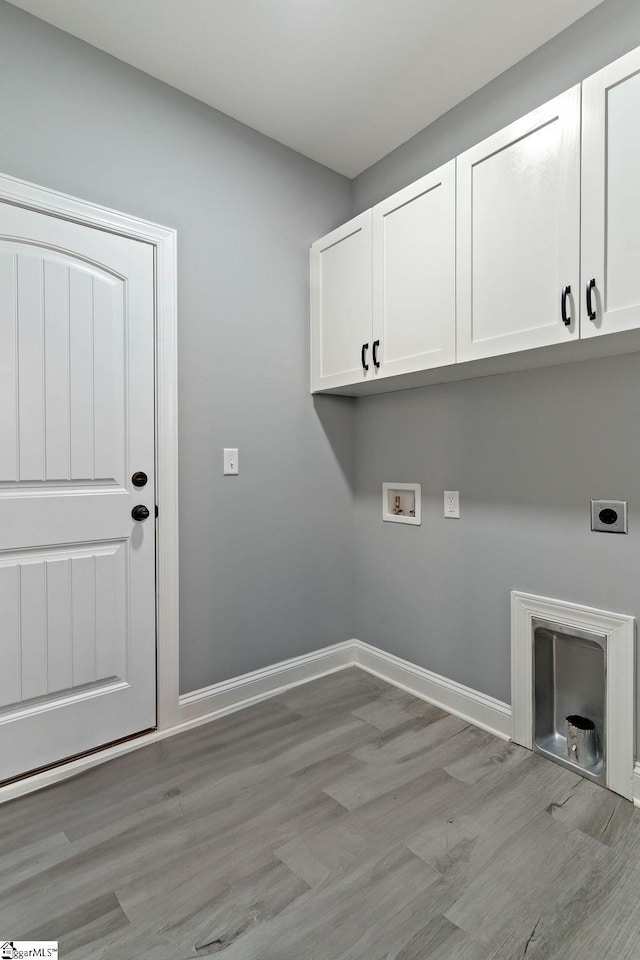 clothes washing area with washer hookup, light wood finished floors, cabinet space, electric dryer hookup, and baseboards