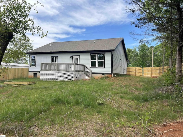 back of property featuring fence, a deck, and a shingled roof