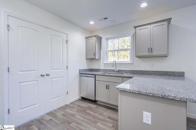 kitchen with gray cabinetry, dishwasher, light wood-type flooring, and sink