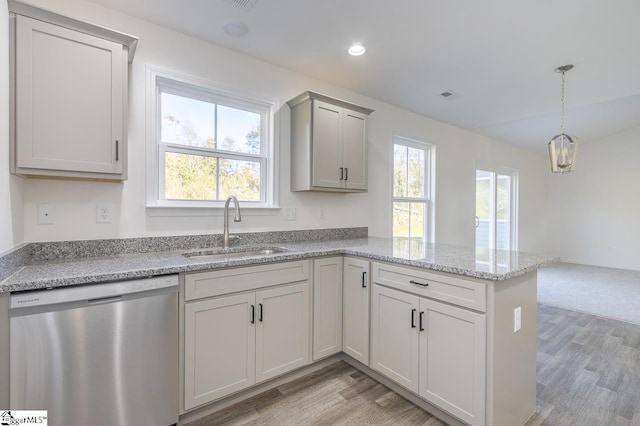 kitchen featuring dishwasher, light hardwood / wood-style floors, decorative light fixtures, and sink