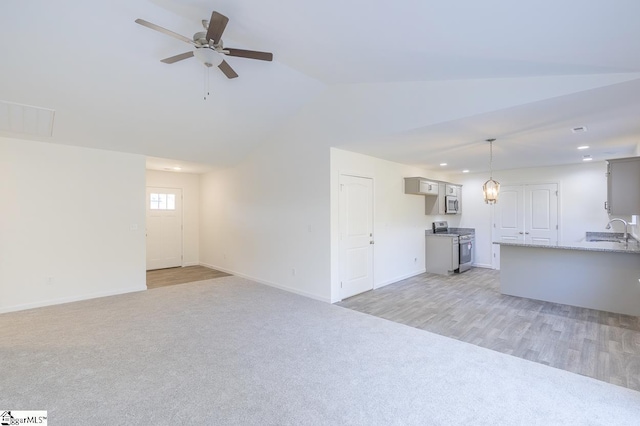 unfurnished living room featuring light hardwood / wood-style floors, ceiling fan, lofted ceiling, and sink