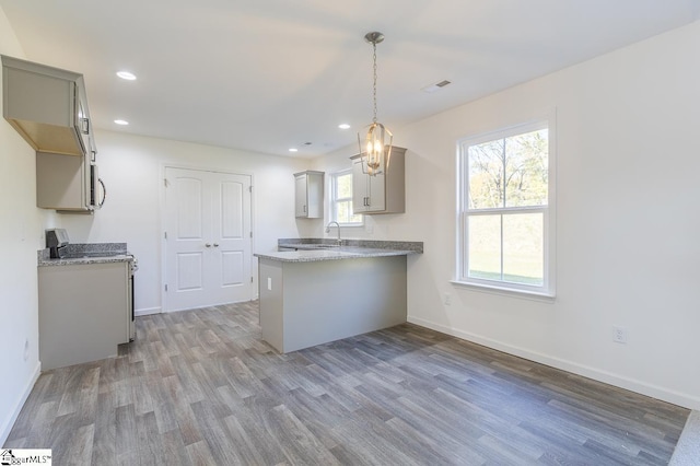 kitchen with range, hanging light fixtures, hardwood / wood-style flooring, gray cabinets, and kitchen peninsula