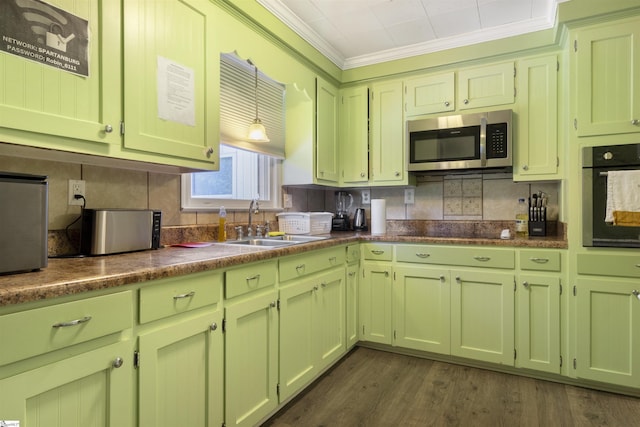 kitchen featuring dark wood-type flooring, sink, hanging light fixtures, ornamental molding, and appliances with stainless steel finishes