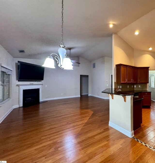 kitchen with lofted ceiling, a breakfast bar, hardwood / wood-style floors, and hanging light fixtures