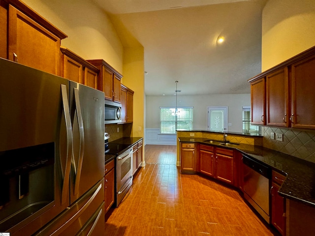 kitchen featuring light hardwood / wood-style flooring, stainless steel appliances, sink, kitchen peninsula, and decorative backsplash