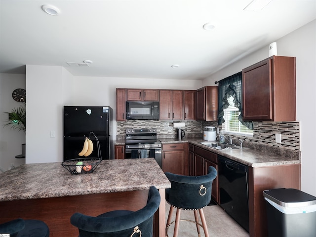 kitchen featuring sink, black appliances, decorative backsplash, and a kitchen breakfast bar