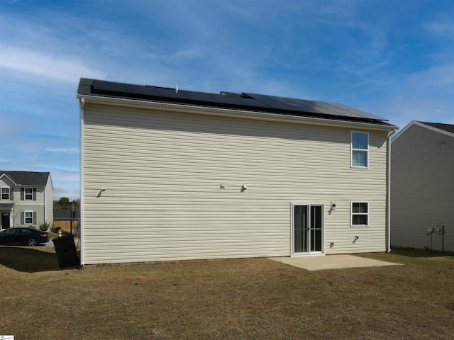 rear view of house with solar panels and a yard