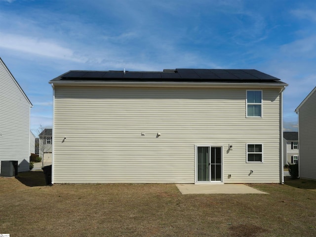 rear view of property with solar panels, central AC unit, a patio area, and a lawn