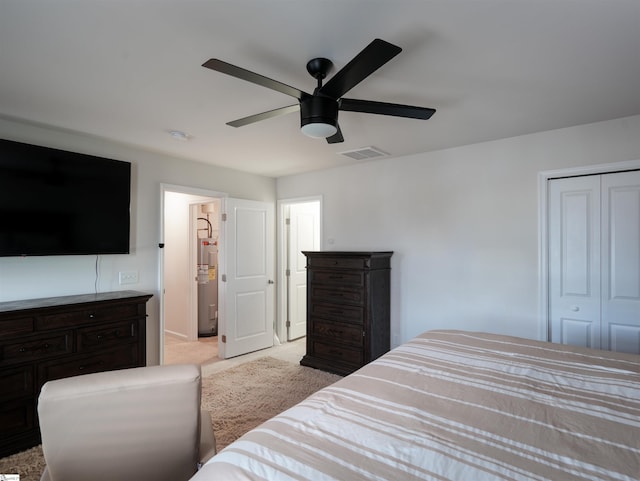 bedroom featuring light carpet, ceiling fan, water heater, and a closet