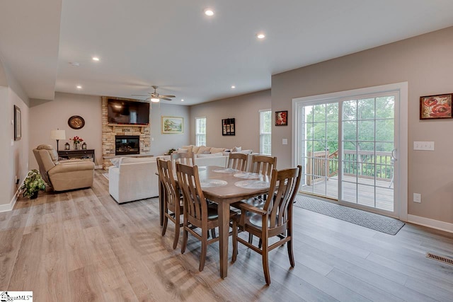 dining area featuring a fireplace, ceiling fan, and light hardwood / wood-style floors