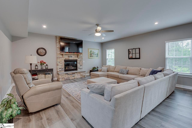 living room featuring light hardwood / wood-style flooring, a fireplace, a healthy amount of sunlight, and ceiling fan