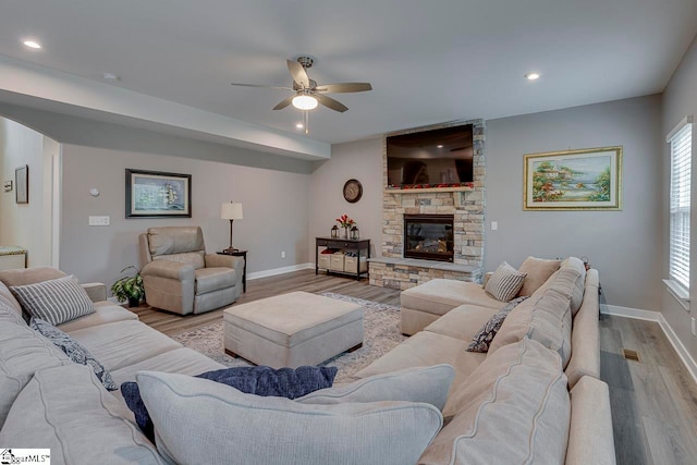 living room with a fireplace, light wood-type flooring, and ceiling fan