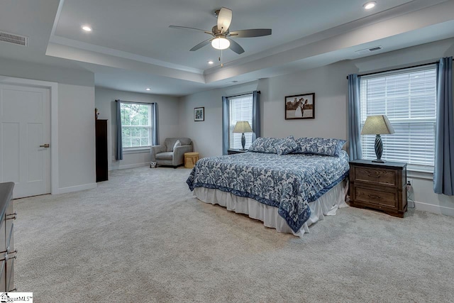 bedroom with ceiling fan, a raised ceiling, and light colored carpet