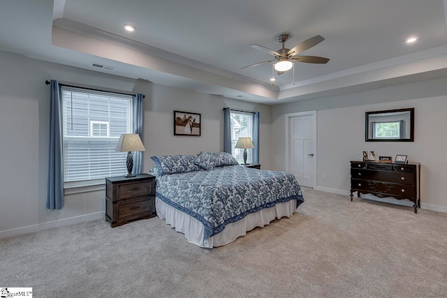 carpeted bedroom featuring ceiling fan and a raised ceiling