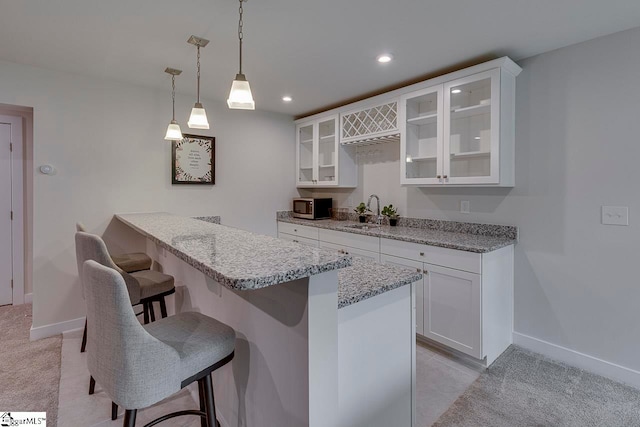 kitchen with white cabinets, light carpet, sink, and a kitchen bar