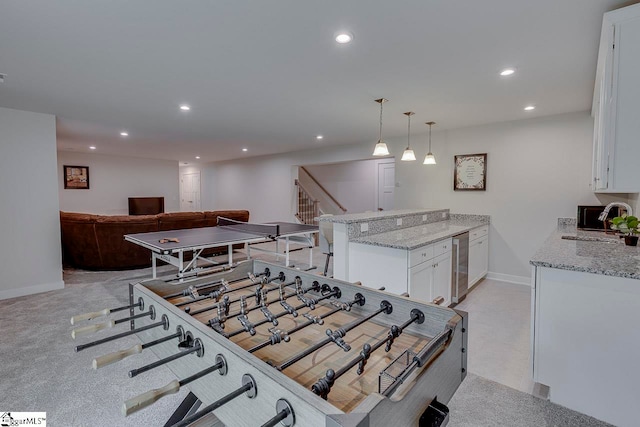 interior space featuring white cabinets, light colored carpet, light stone counters, and kitchen peninsula