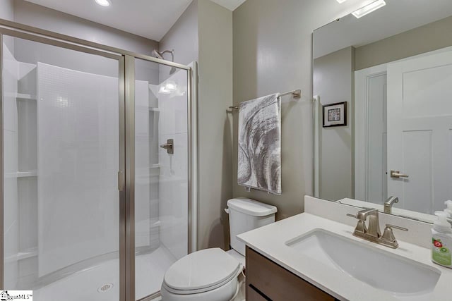 bathroom featuring vanity, toilet, and a shower with door