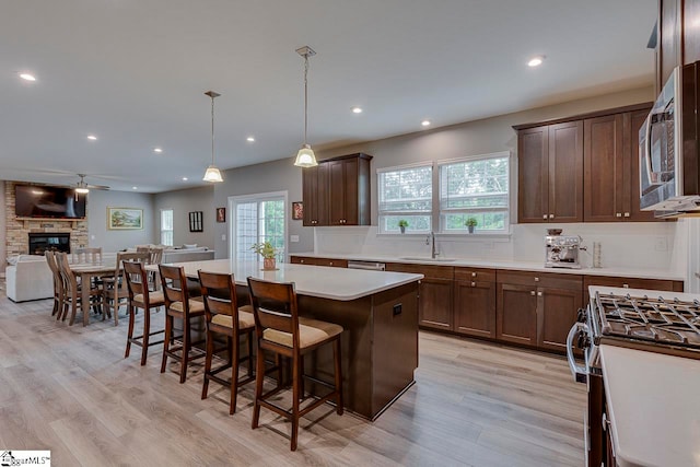 kitchen featuring tasteful backsplash, stainless steel appliances, a fireplace, a kitchen island, and light wood-type flooring