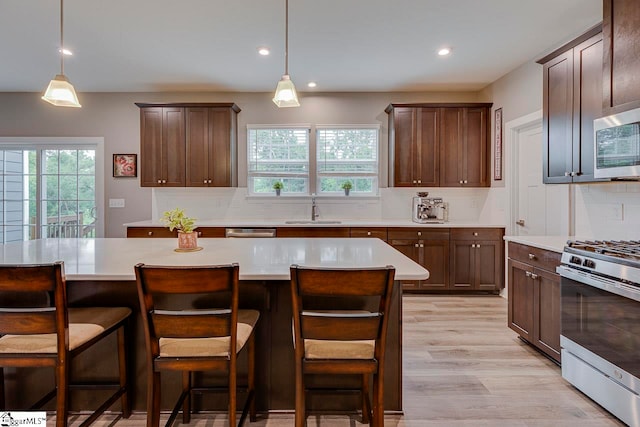 kitchen with appliances with stainless steel finishes, a wealth of natural light, decorative backsplash, and sink