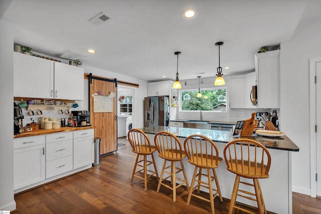 kitchen with appliances with stainless steel finishes, a barn door, and white cabinetry