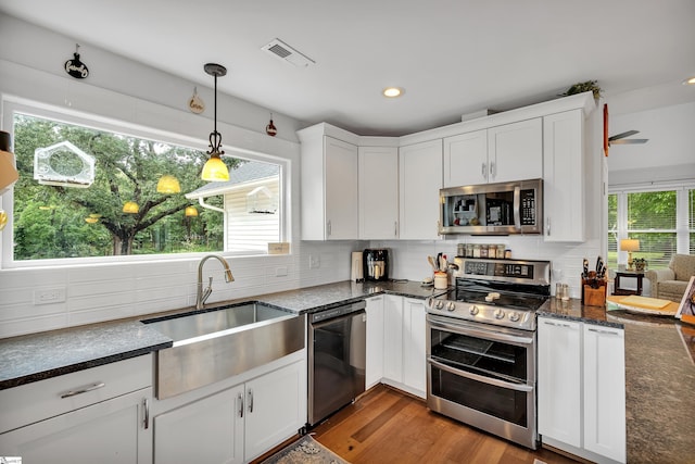 kitchen with decorative light fixtures, tasteful backsplash, stainless steel appliances, white cabinets, and light wood-type flooring