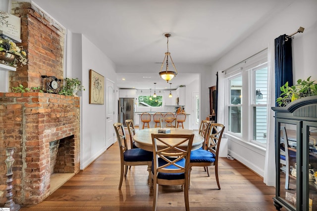 dining area with brick wall, a fireplace, and wood-type flooring