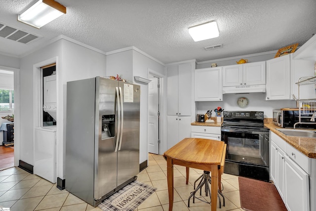 kitchen with stacked washer / dryer, white cabinets, stainless steel appliances, and light tile patterned floors