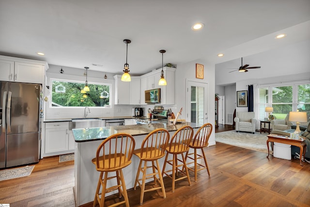 kitchen with appliances with stainless steel finishes, hardwood / wood-style flooring, and white cabinets