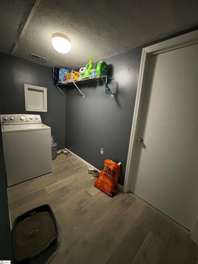 clothes washing area with a textured ceiling, washer / clothes dryer, and wood-type flooring