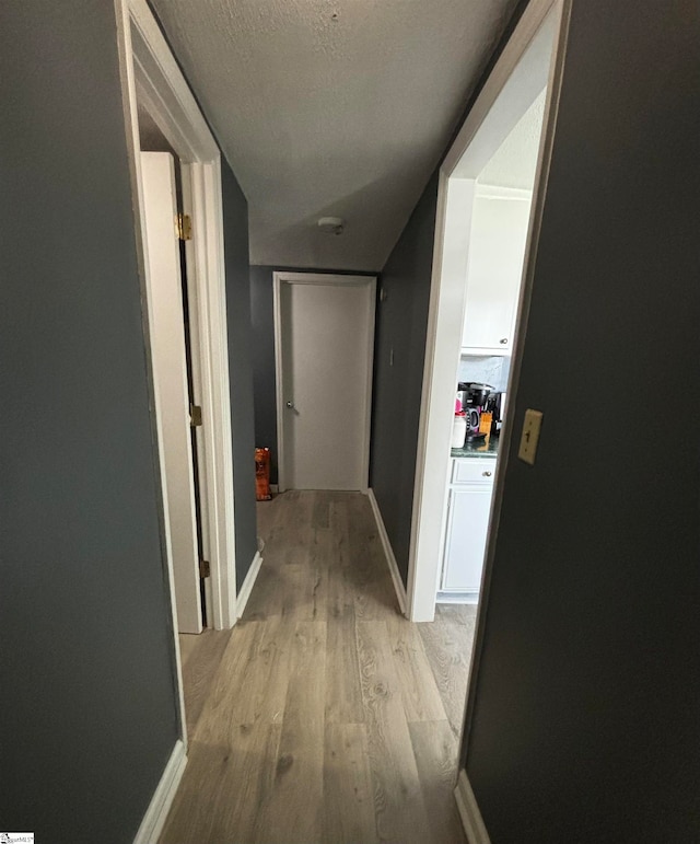 corridor featuring light hardwood / wood-style floors and a textured ceiling