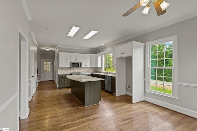 kitchen with appliances with stainless steel finishes, a wealth of natural light, a center island, and hardwood / wood-style floors