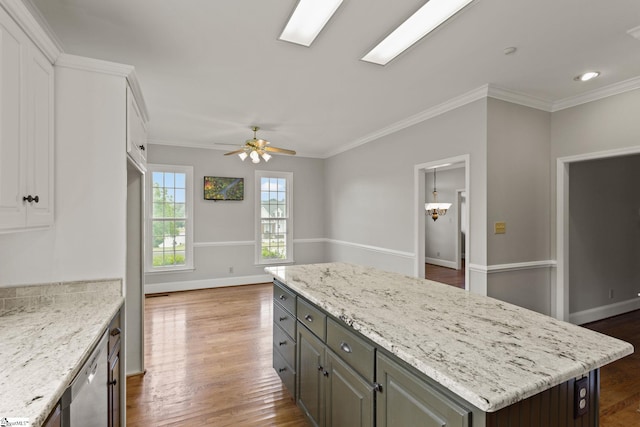 kitchen with wood-type flooring, a kitchen island, ceiling fan, ornamental molding, and white cabinetry