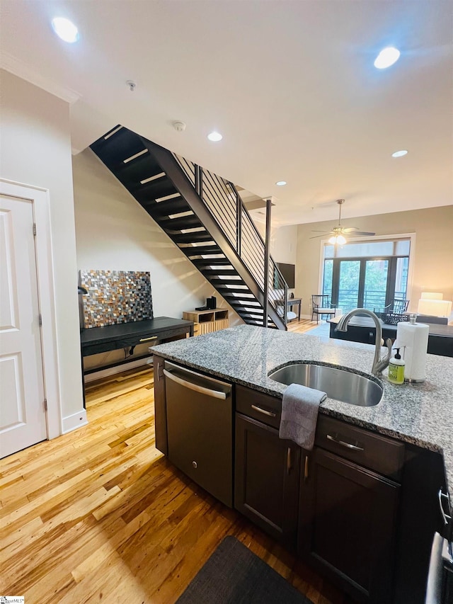 kitchen featuring dishwasher, light wood-type flooring, ceiling fan, sink, and dark stone counters