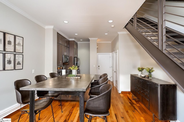 dining room with ornamental molding and light hardwood / wood-style flooring