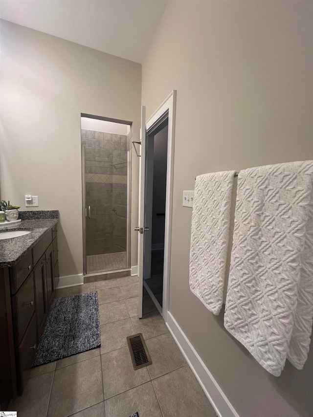 bathroom featuring a shower with shower door, vanity, and tile patterned flooring