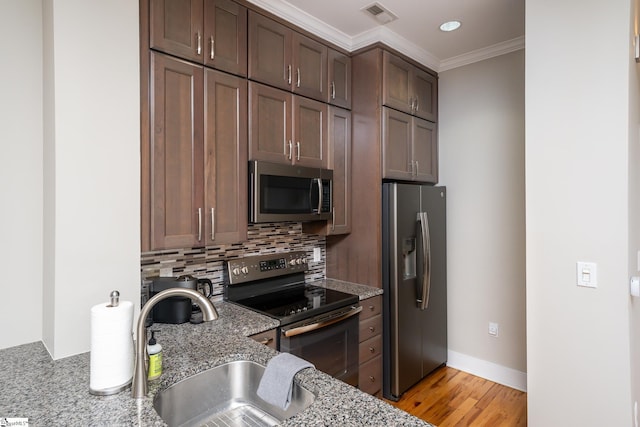 kitchen with sink, light stone counters, crown molding, appliances with stainless steel finishes, and backsplash