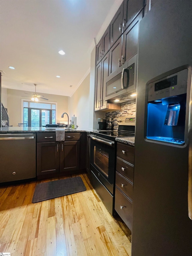 kitchen featuring light hardwood / wood-style flooring, ceiling fan, kitchen peninsula, backsplash, and stainless steel appliances