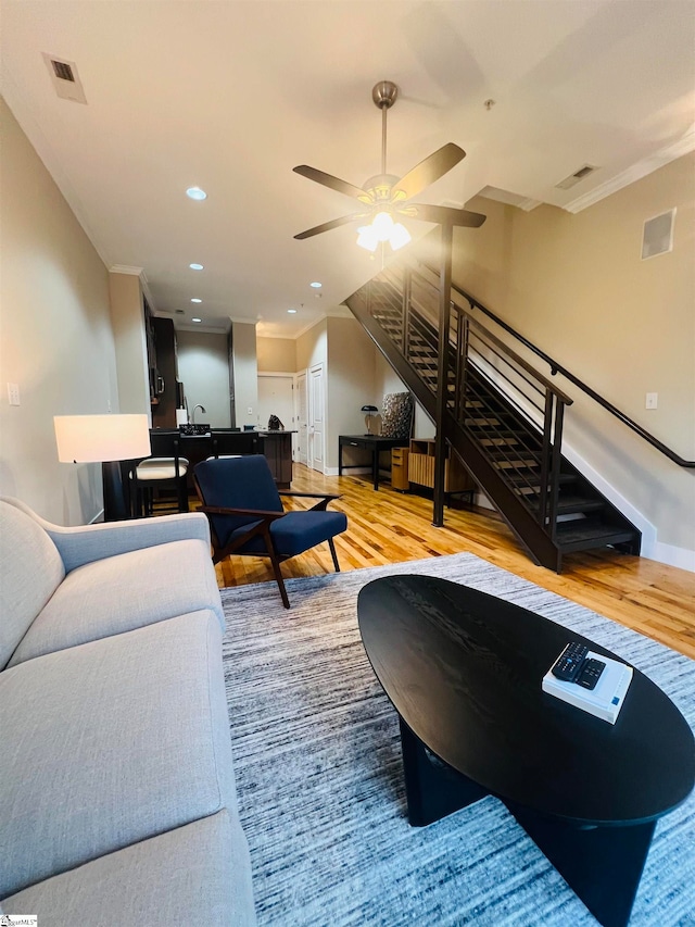 living room featuring ceiling fan, light wood-type flooring, and ornamental molding