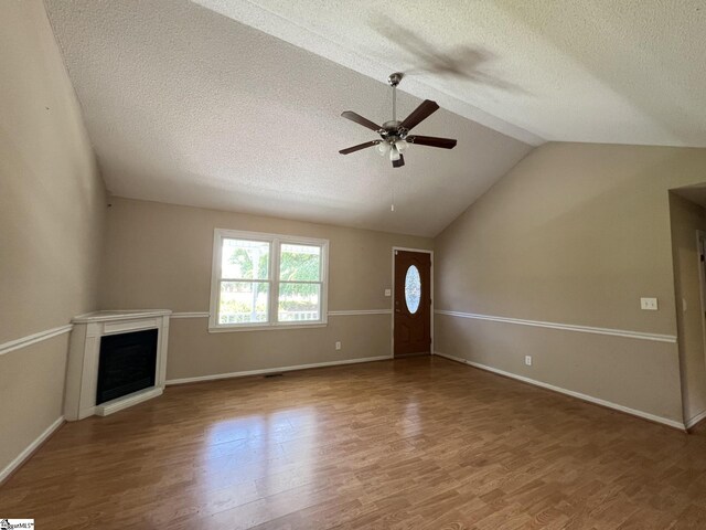 unfurnished living room with ceiling fan, a textured ceiling, hardwood / wood-style floors, and lofted ceiling