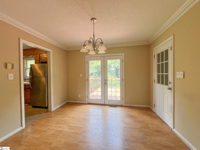 unfurnished dining area featuring an inviting chandelier, french doors, light wood-type flooring, and a textured ceiling